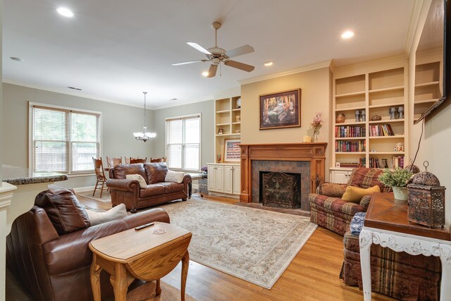 living room featuring recessed lighting, ceiling fan with notable chandelier, a premium fireplace, light wood finished floors, and crown molding