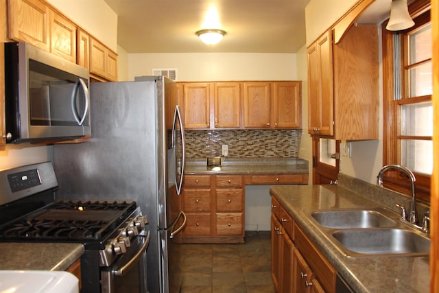 kitchen with stainless steel appliances, tasteful backsplash, visible vents, brown cabinetry, and a sink