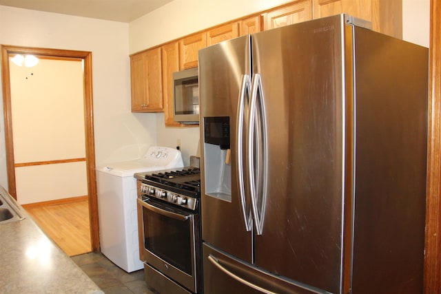 kitchen with washer / dryer, appliances with stainless steel finishes, and light countertops