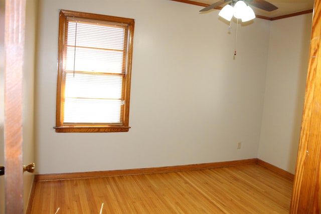 spare room featuring ceiling fan, ornamental molding, light wood-style flooring, and baseboards