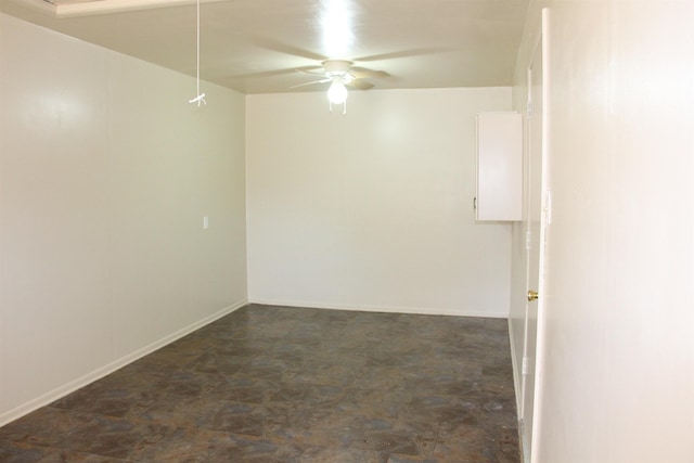 empty room with attic access, ceiling fan, and baseboards