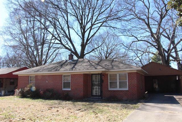 ranch-style home with driveway, brick siding, and a chimney