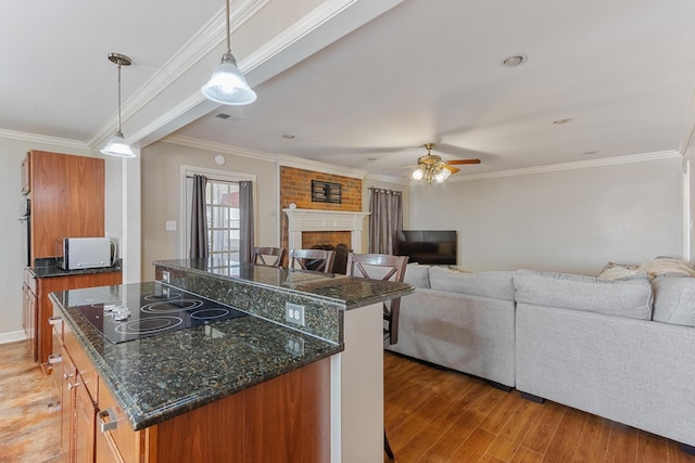 kitchen with brown cabinets, white microwave, open floor plan, a kitchen island, and black electric cooktop