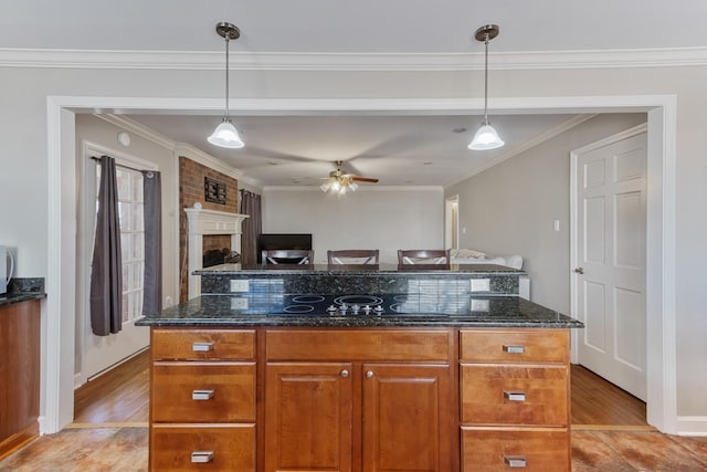 kitchen with light wood-type flooring, black electric stovetop, ornamental molding, and dark stone counters