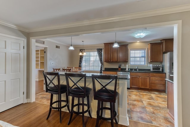 kitchen featuring dishwasher, dark countertops, a breakfast bar, pendant lighting, and a sink