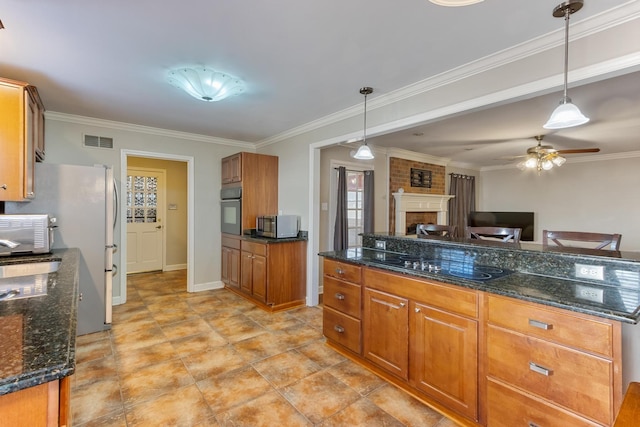 kitchen featuring black appliances, brown cabinetry, a brick fireplace, and visible vents