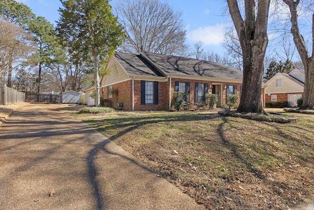 ranch-style house featuring a garage, a front yard, fence, and brick siding