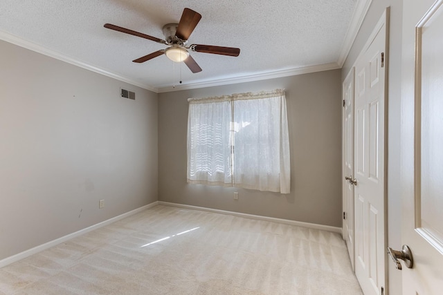 carpeted empty room with a ceiling fan, crown molding, a textured ceiling, and baseboards