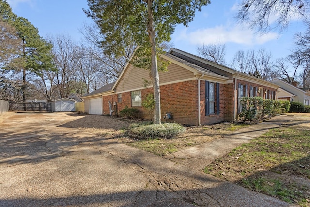 view of home's exterior with a garage, fence, concrete driveway, and brick siding