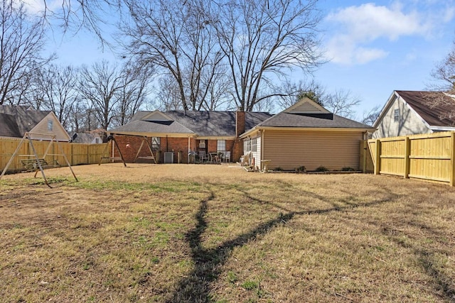 back of house featuring brick siding, a fenced backyard, and a yard