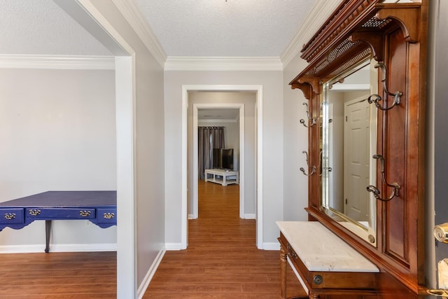 corridor featuring crown molding, a textured ceiling, baseboards, and wood finished floors