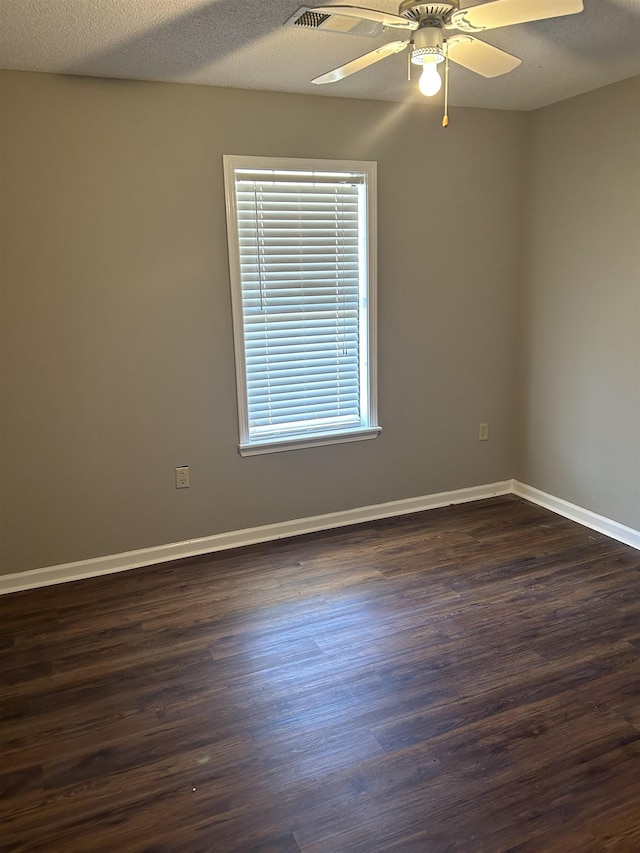 empty room featuring a ceiling fan, dark wood finished floors, a textured ceiling, and baseboards