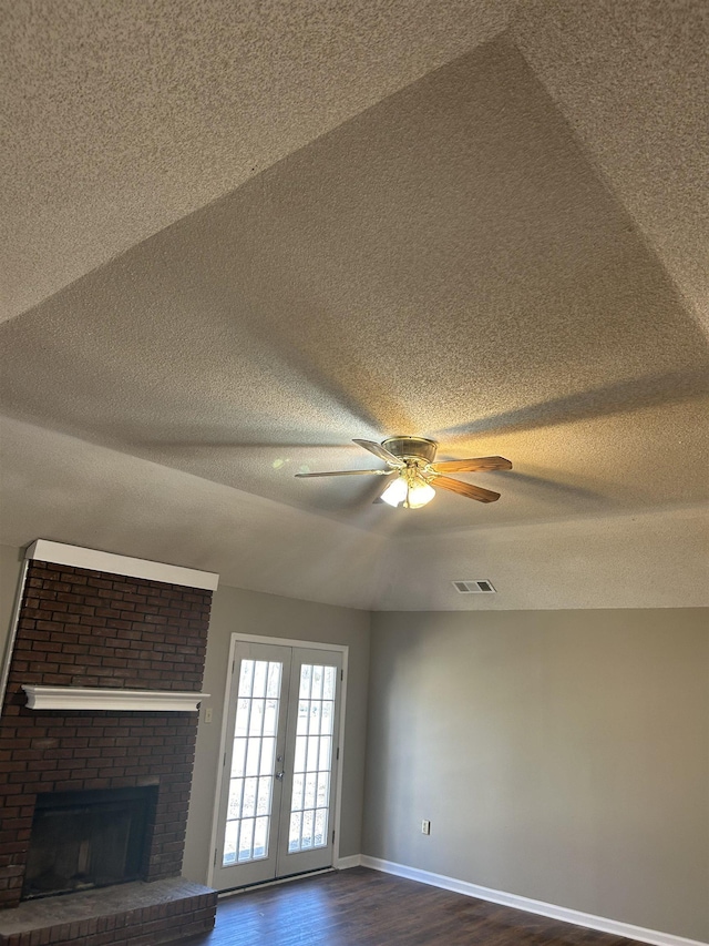 unfurnished living room with a fireplace, visible vents, dark wood-type flooring, a textured ceiling, and baseboards