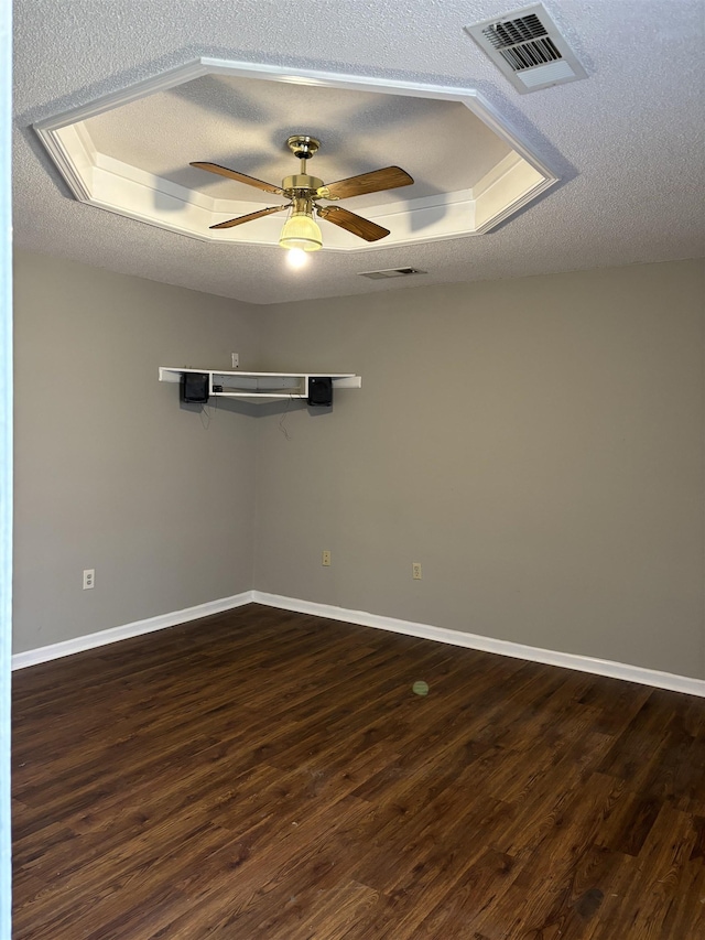 unfurnished room featuring a textured ceiling, dark wood-style flooring, a raised ceiling, and visible vents