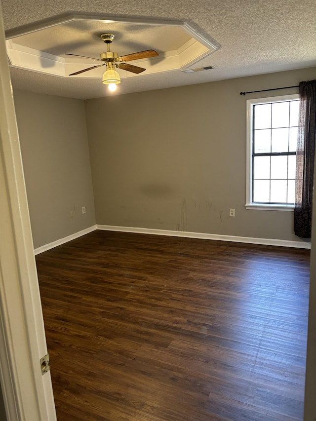 spare room with dark wood-style floors, a tray ceiling, ceiling fan, a textured ceiling, and baseboards