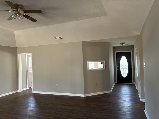 entrance foyer featuring dark wood-type flooring, lofted ceiling, visible vents, and baseboards