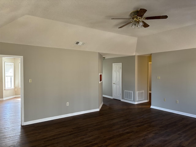 spare room with lofted ceiling, dark wood-type flooring, and visible vents