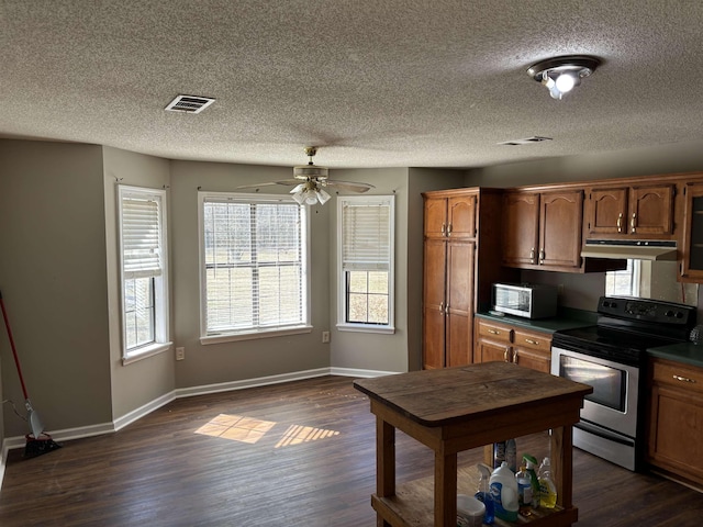 kitchen with dark countertops, dark wood-style floors, visible vents, and appliances with stainless steel finishes