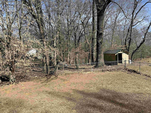 view of yard with a forest view, an outdoor structure, and fence