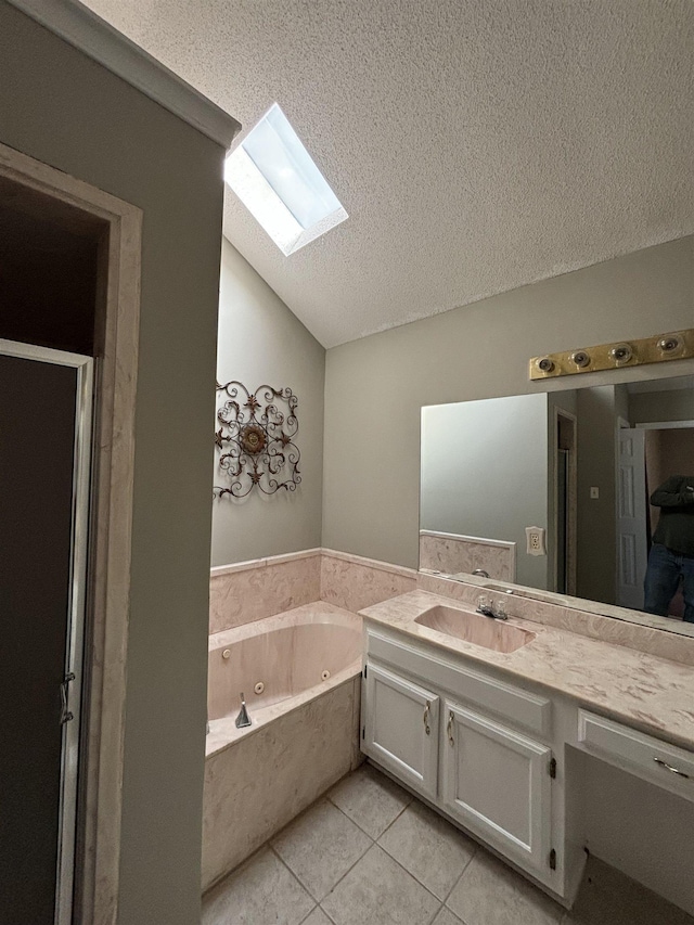 bathroom with vaulted ceiling with skylight, a tub with jets, tile patterned floors, a textured ceiling, and vanity