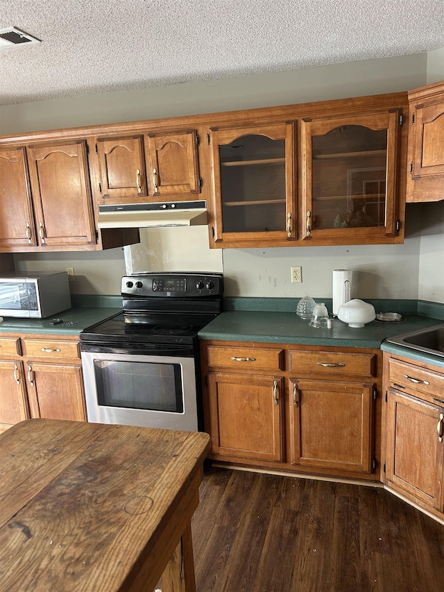 kitchen with dark wood-style flooring, stainless steel appliances, dark countertops, glass insert cabinets, and under cabinet range hood