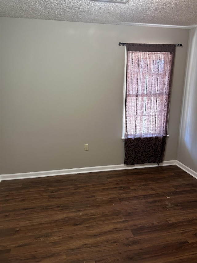 empty room with a textured ceiling, baseboards, and dark wood-style flooring