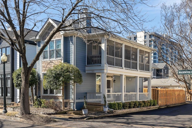 view of front of house featuring a sunroom, covered porch, and fence