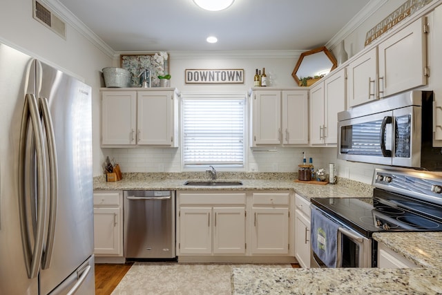 kitchen featuring visible vents, stainless steel appliances, a sink, and ornamental molding