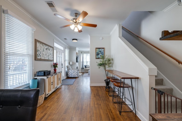 foyer entrance featuring ornamental molding, visible vents, stairway, and wood finished floors