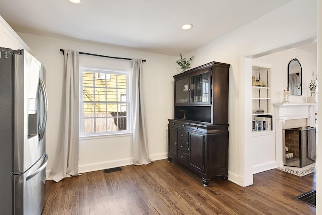 unfurnished dining area featuring dark wood-style floors, a fireplace with flush hearth, visible vents, and recessed lighting