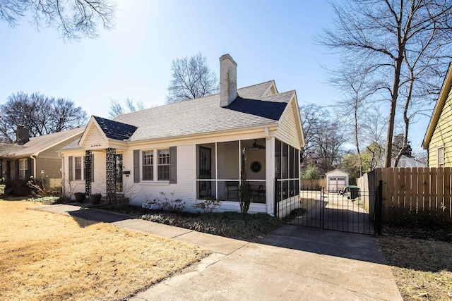 exterior space with brick siding, fence, a sunroom, a gate, and a chimney