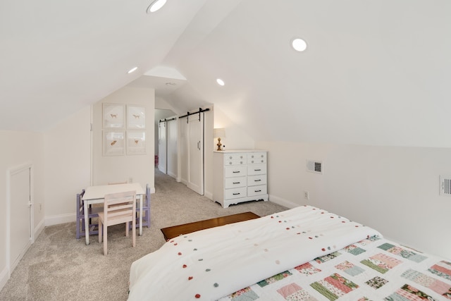 bedroom featuring lofted ceiling, light carpet, visible vents, and a barn door