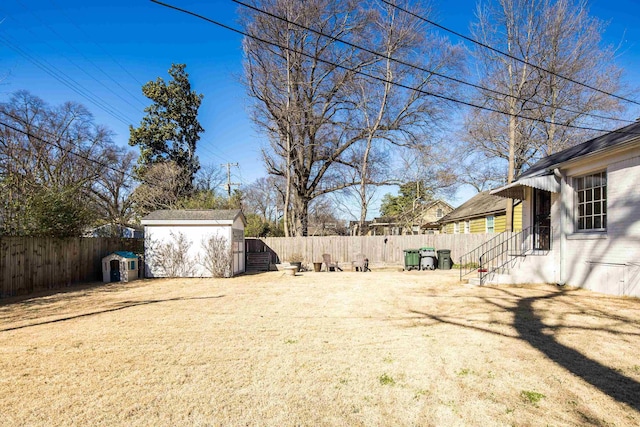 view of yard with entry steps, a storage unit, an outdoor structure, and a fenced backyard