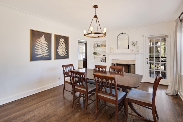 dining space with baseboards, dark wood-style floors, built in shelves, a chandelier, and a fireplace