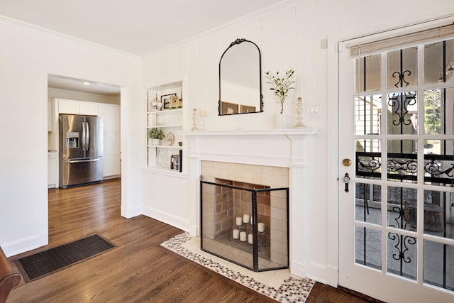 living room with baseboards, visible vents, a tile fireplace, ornamental molding, and wood finished floors