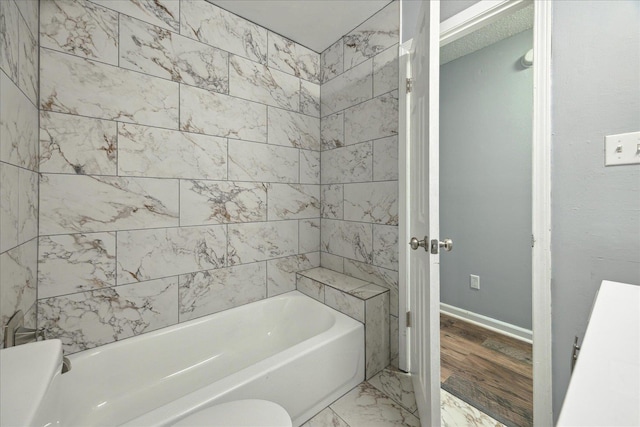 full bath with a bathtub, marble finish floor, toilet, and baseboards