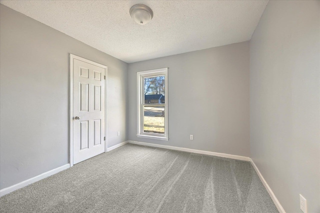 spare room with carpet, baseboards, and a textured ceiling