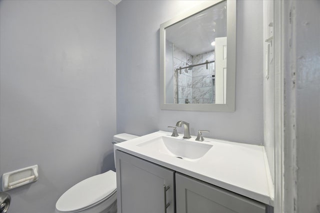 bathroom featuring toilet, tiled shower, and vanity