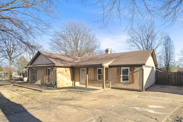 rear view of house with roof with shingles, a chimney, and fence