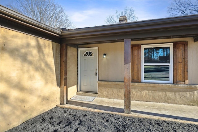 view of exterior entry featuring a chimney