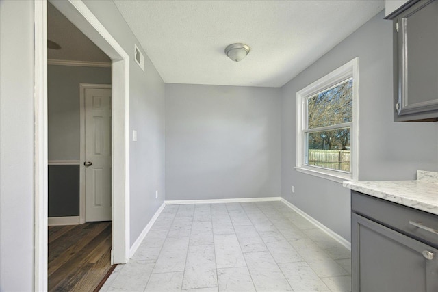 unfurnished dining area featuring a textured ceiling, visible vents, and baseboards