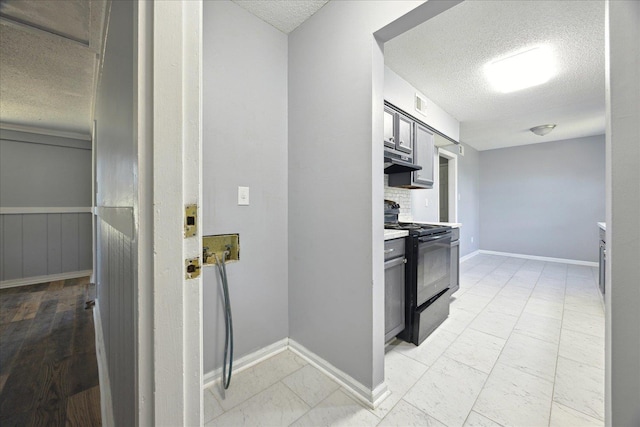 kitchen with decorative backsplash, light countertops, a textured ceiling, under cabinet range hood, and gas stove