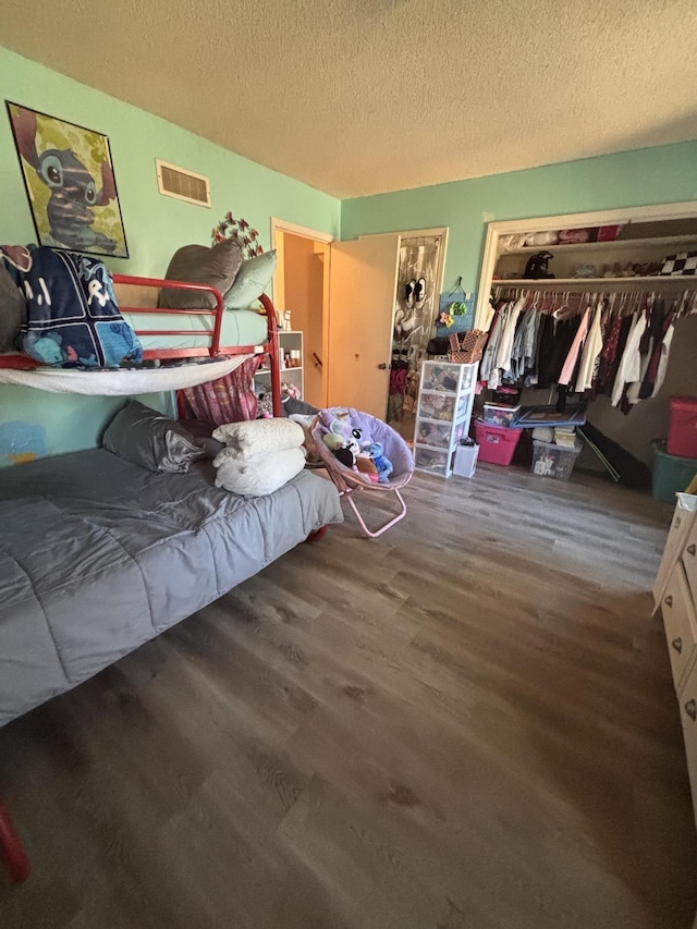 bedroom with a textured ceiling, wood finished floors, and visible vents