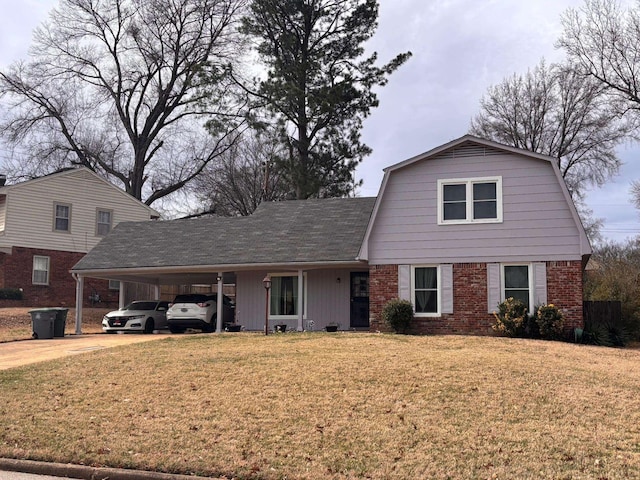 colonial inspired home with brick siding, a front yard, an attached carport, and a gambrel roof