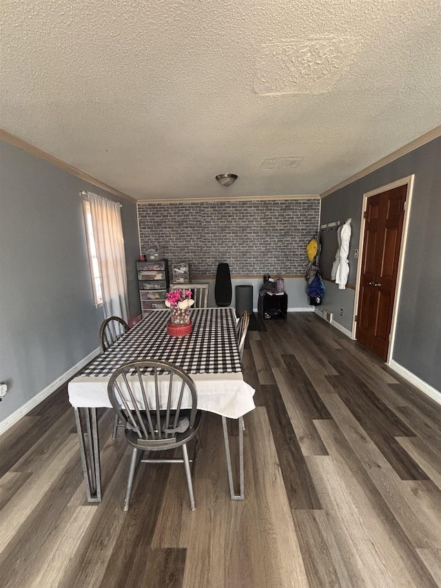 dining area featuring brick wall, crown molding, baseboards, and wood finished floors