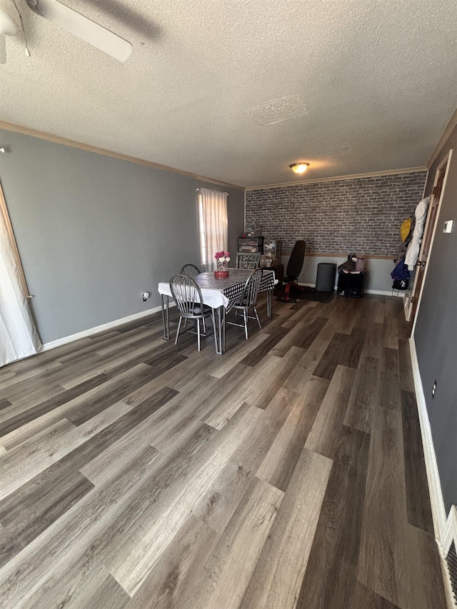 unfurnished dining area featuring baseboards, brick wall, wood finished floors, and crown molding