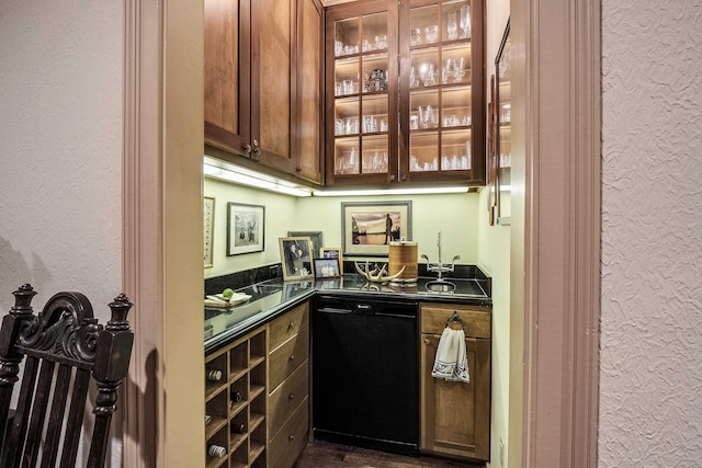 bar with black dishwasher, a textured wall, and indoor wet bar