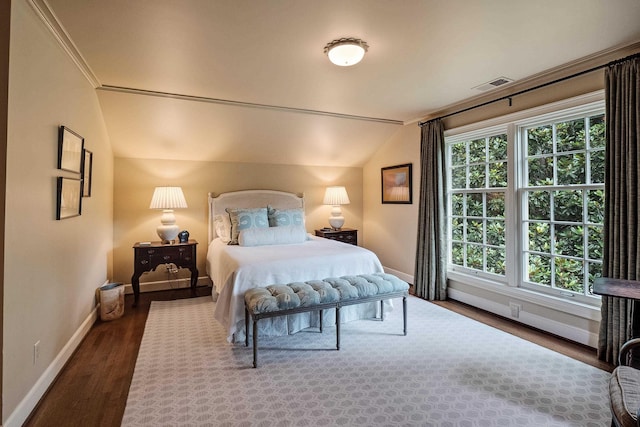 bedroom with baseboards, visible vents, vaulted ceiling, and wood finished floors