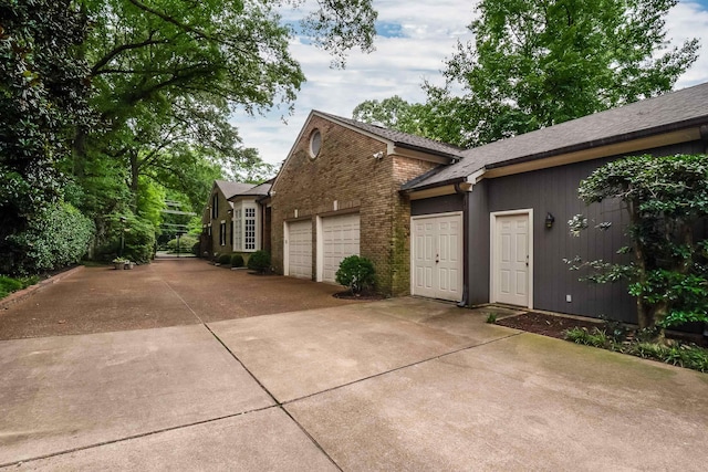 view of front of home with driveway, an attached garage, a shingled roof, and brick siding