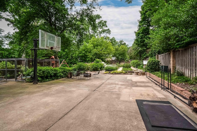 view of sport court with a playground and fence